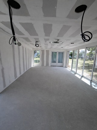 Placo et doublage mural dans maison à Lagord avec grandes baies vitrées et plafond en plaque de plâtre en cours de réalisation