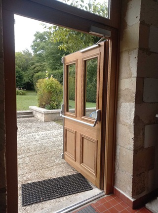 Vue intérieure d'une porte en bois avec barre anti-panique installée lors d'une rénovation à La Rochelle.