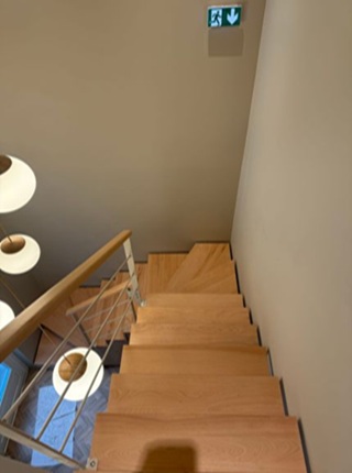 Escalier en hêtre vernis dans hôtel a la rochelle avec garde corps métal et finition soignée