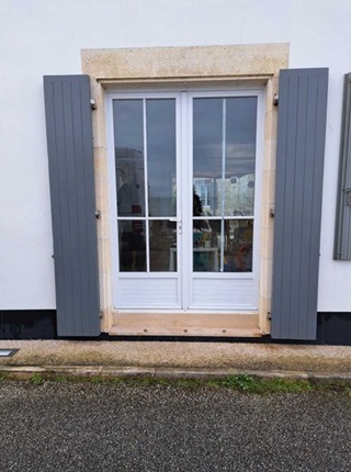 Volet battant en bois gris installé en neuf à Périgny sur façade blanche avec menuiserie extérieure et porte fenêtre