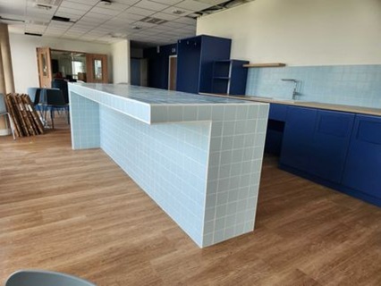 Ilot central en melamine avec carrelage bleu clair dans des locaux professionnels EDF à Périgny, projet neuf mobilier