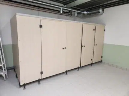 Ensemble de cloisons compactes pour sanitaires de piscine à Saintes avec portes bois clair dans un projet de rénovation