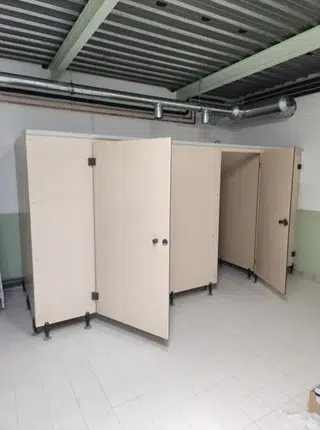 Cellules WC en cloison compacte bois clair avec portes ouvertes dans une piscine rénovée à Saintes