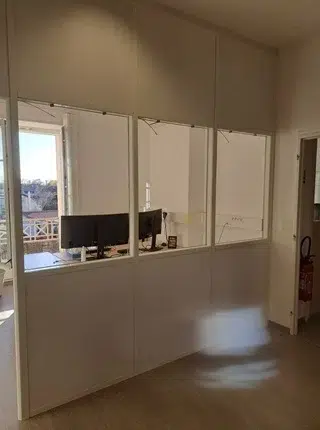 Cloison modulaire blanche avec trois fenêtres vitrées installée dans des bureaux rénovés à Saintes pour structurer les espaces de travail
