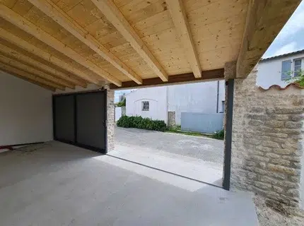 Portail en aluminium gris installé lors d’un projet de rénovation à Lagord avec muret en pierre et entrée de maison